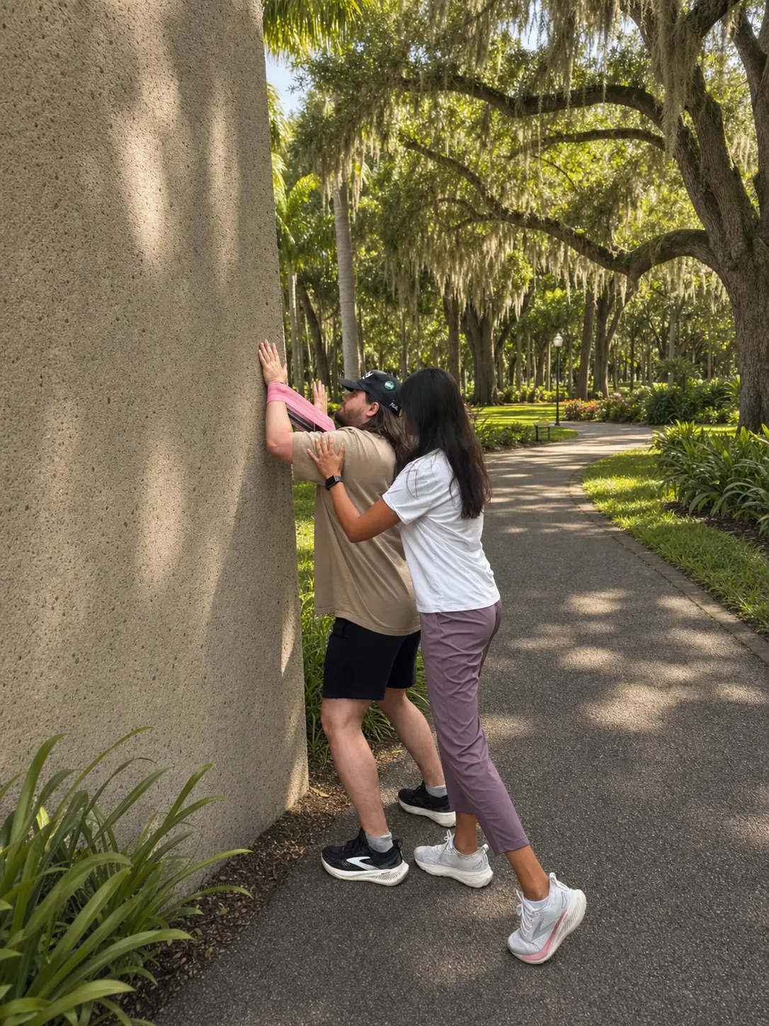 Alisha guiding a patient through a standing mobility stretch outdoors in Tampa