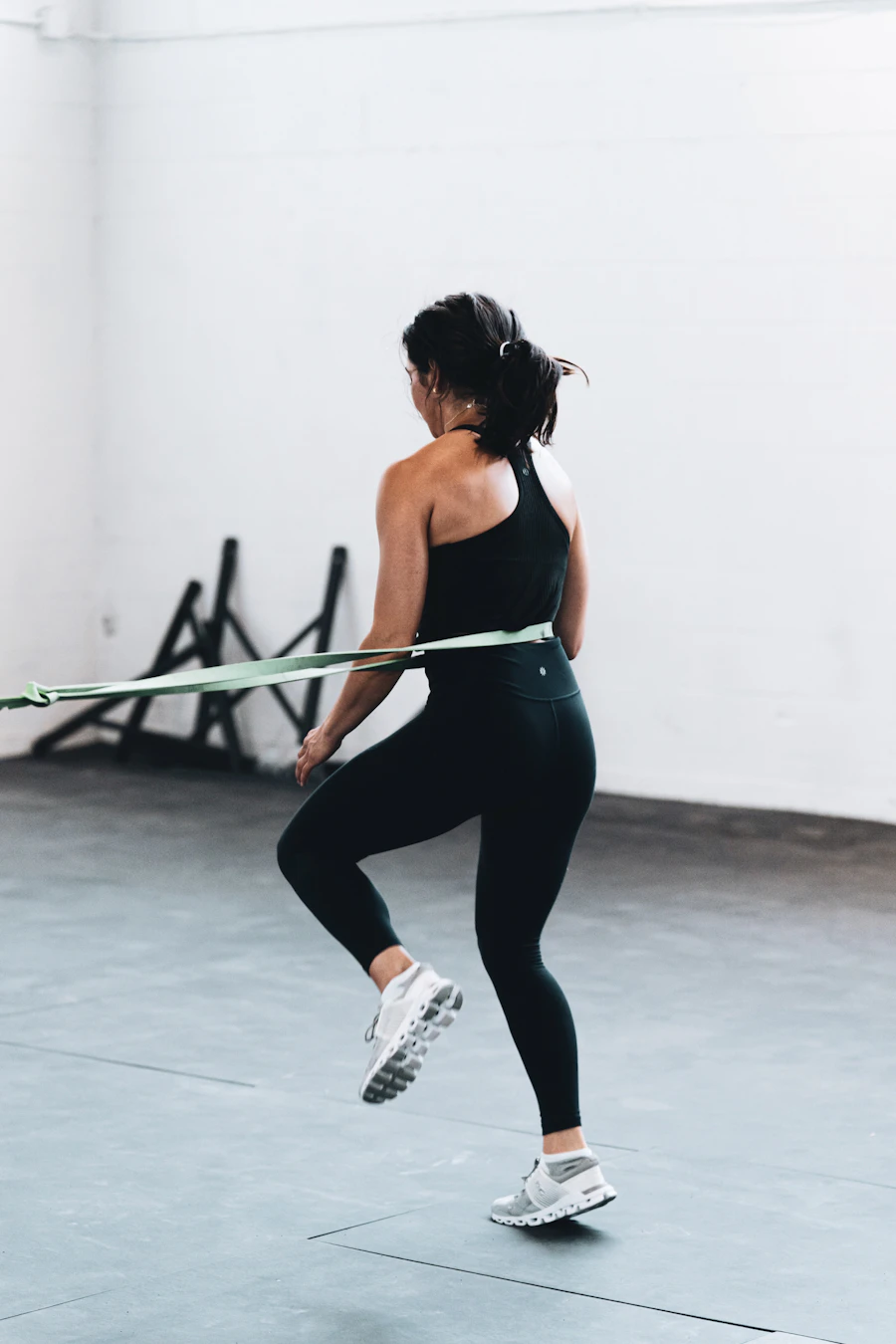 Person doing a single-leg resistance-band strengthening exercise in a bright studio